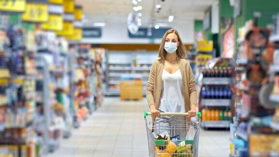 在隔离期间一名年轻女子推着一辆购物车在超市里购买食品杂货一位戴着医用口罩的妇女在商店里走来走去在流感期间她戴着个人防护设备4kProRes