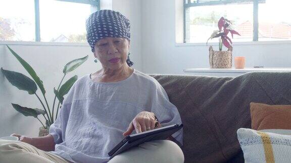 身患癌症的老年女性在家里的沙发上使用平板电脑
