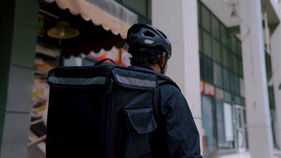 背包工作的送货员骑着自行车在城市里为客户和客户送订单
