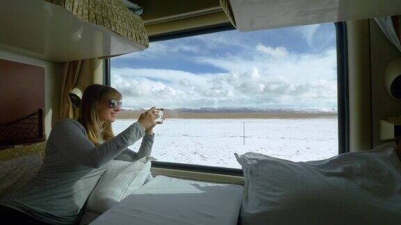 近距离观察:一名女子在火车上拍摄西藏雪景