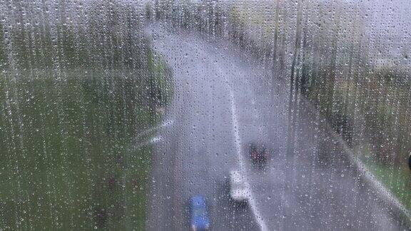 透过湿漉漉的窗户看马路上有雨滴在雨中有人们的倒影