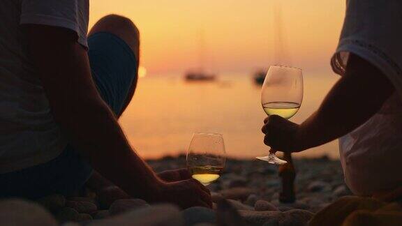 一对夫妇在日落时分的意大利厄尔巴岛海滩上喝酒
