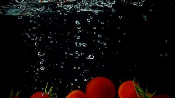 在黑暗的背景下整个番茄从水中缓缓落下