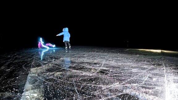 家庭是滑冰之夜女孩和男孩在大自然中骑着花样滑冰鞋母亲女儿和儿子一起骑在裂缝的冰上冬季户外运动对运动员来说是一种乐趣