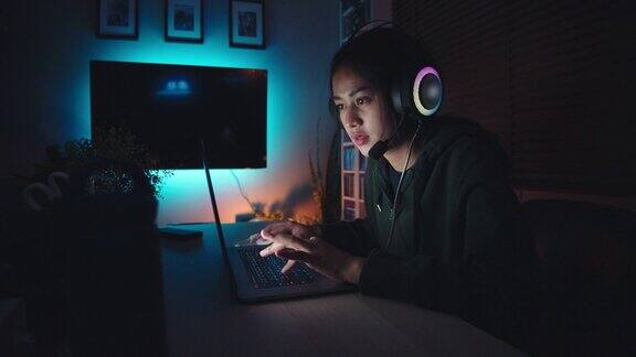 亚洲年轻女子晚上在笔记本电脑上玩网络游戏