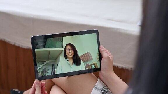 一名亚洲妇女在家里用数码平板电脑视频聊天