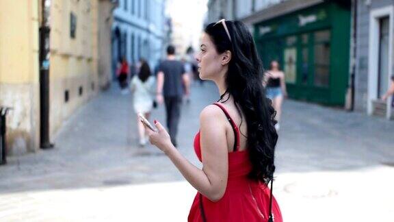 美丽的女孩拿着手机在街上-慢镜头