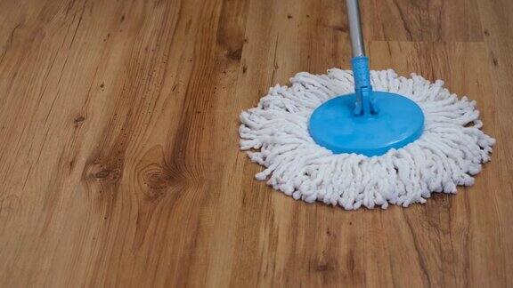 正面视图一个平坦的湿拖把慢慢地擦拭客厅的拼花地板左右