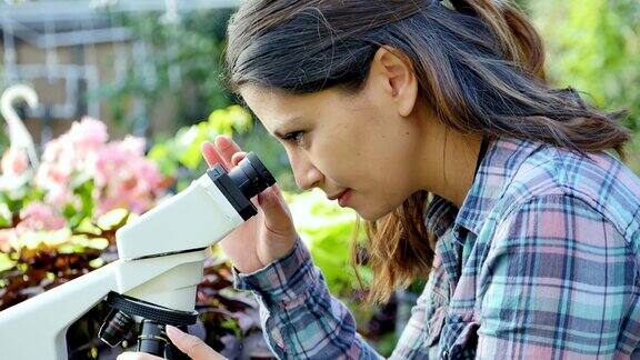 自信的女植物学家在显微镜下检查植物样本