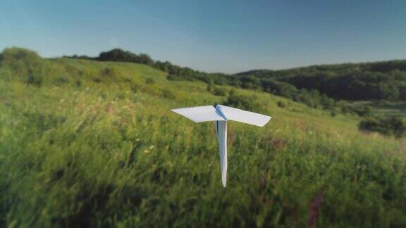 一架真正的纸飞机正飞过一个风景如画的山谷跟随拍摄