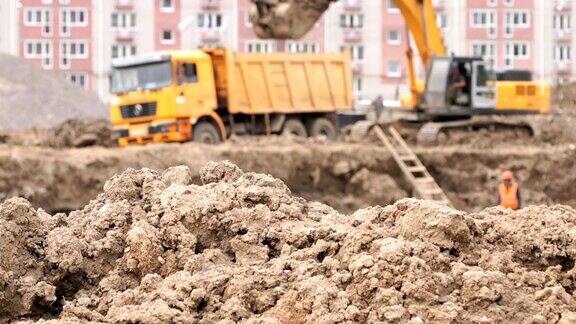 挖掘机用铲斗将粘土装入自卸卡车