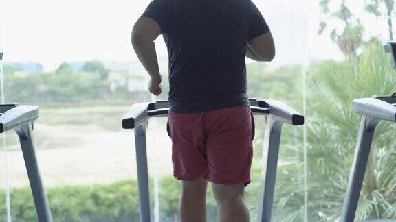 完全的男性在健身房的跑步机上跑步减肥和运动后视图