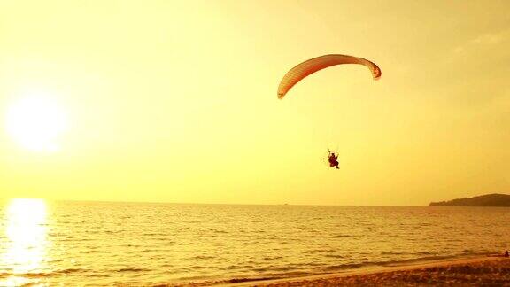 热带海滩上日落时滑翔伞的剪影