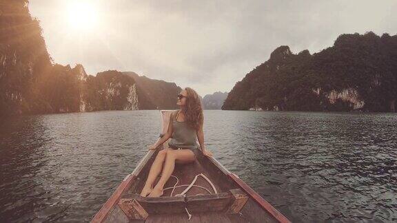 生活方式视频漂亮的旅行女人坐在木头长尾船在热带石灰岩悬崖探索和度假泰国KhaoSok湖