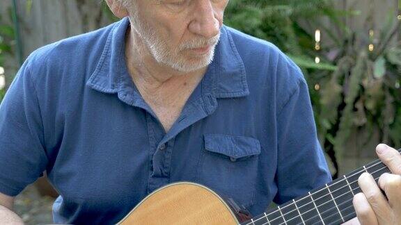 有魅力的老人在外面学习弹原声吉他