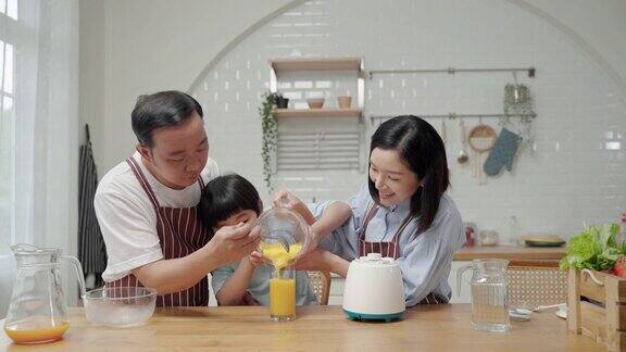 一个亚洲家庭爸爸妈妈和儿子在厨房帮忙做饭做冰沙