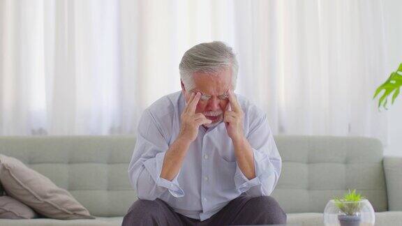 亚洲老年男子头痛、偏头痛等病痛和病痛都躺在家里的沙发上养老理念