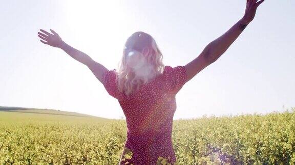 一名年轻女子在油菜花盛开的田野里放松的4k视频片段