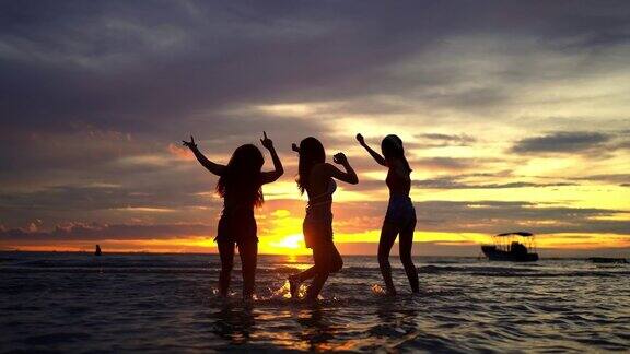 4K剪影一群亚洲女子在夏日夕阳下的热带海岛海滩上跳舞