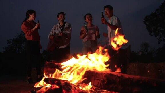 朋友们在野外露营时在火边跳舞、弹吉他