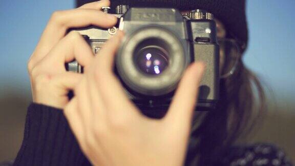 十几岁的女孩在海滩上用一个旧胶卷相机拍照