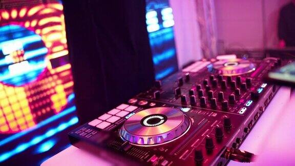 DJ的手在拧着DJ的遥控器上的不同按钮俱乐部里的颜色和轻音乐与dj派对