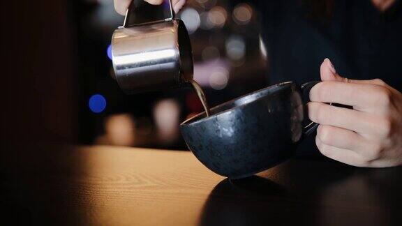 专业咖啡店的咖啡师正在做拿铁职业女性将新鲜的美式咖啡倒入黑色陶瓷杯中