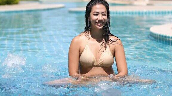 在炎热的夏天妇女们穿着比基尼在游泳池游泳喝着鸡尾酒