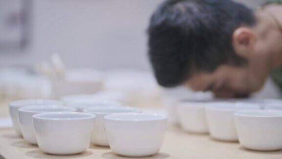 3名亚洲华裔男咖啡师品酒师表演杯咖啡品尝杯咖啡后在剪贴板上写下