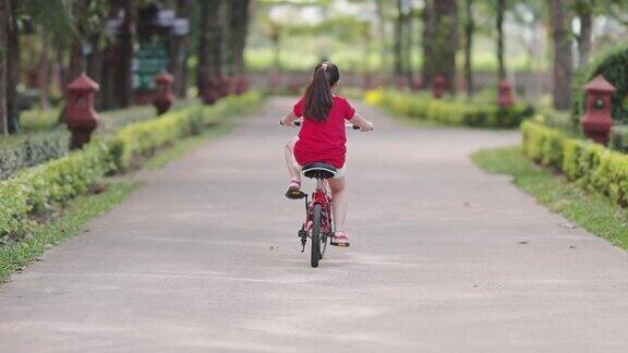 快乐的亚洲女孩在公园里骑自行车