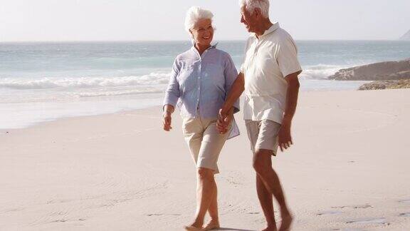 一对浪漫的老年夫妇在夏天沿着海滩散步
