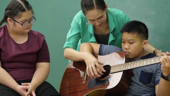 老师在教室里教残疾儿童吉他非常开心