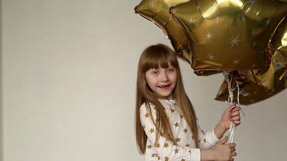 一个可爱的小女孩穿着皮达姆手里拿着金色的球和星星