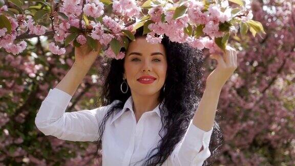美丽的黑发触摸樱花盛开的树枝