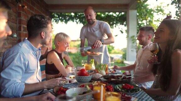 派对主持一个厨师为他的朋友提供烧烤在夏季早午餐