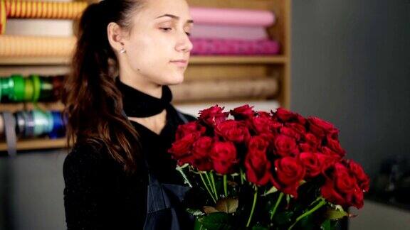 年轻迷人的女花商在花店安排美丽的红玫瑰花束Slowmotion拍摄
