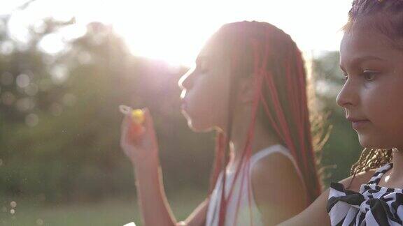 有趣的小女孩吹肥皂泡在夏天的自然快乐的童年概念