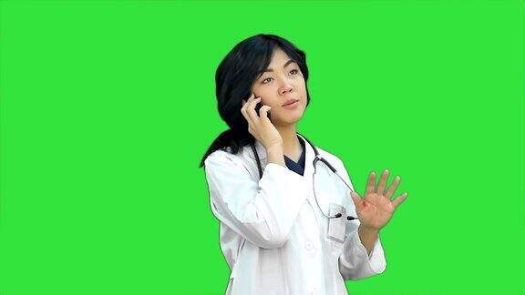沉思的亚洲女医生使用智能手机在一个绿色屏幕色度键