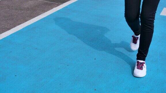慢动作女子在体育场的蓝色跑道上跑步