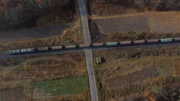俯视图货运列车通过铁路道口无人机视图飞行在铁路轨道和沥青道路交叉口