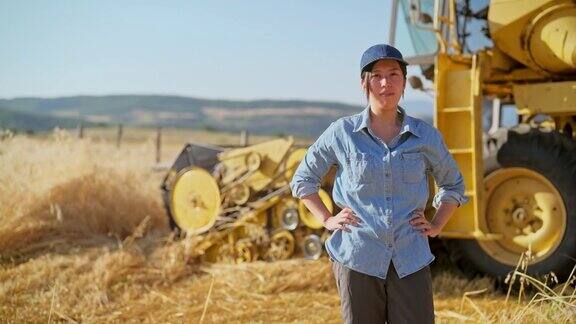 年轻的女农民的肖像与联合收割机在农田