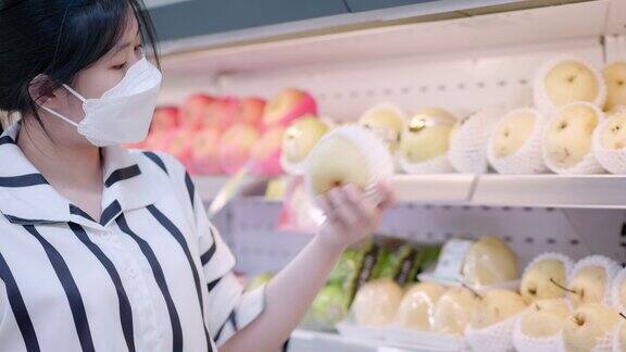 亚洲少女戴着口罩走在超市买杂货