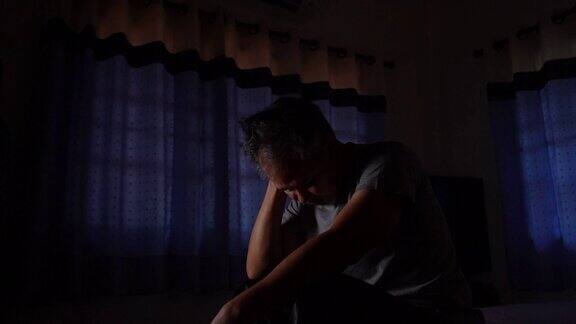 失眠老人在黑暗中不开心夜不能寐亚洲男子坐在床上遭受失眠和睡眠障碍