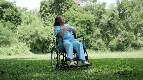 孤独的残疾老年妇女独自坐在轮椅上在公园里