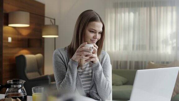 年轻女子一边喝咖啡一边用笔记本电脑
