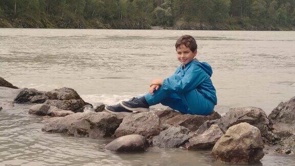 夏天小男孩坐在山河边的石头上