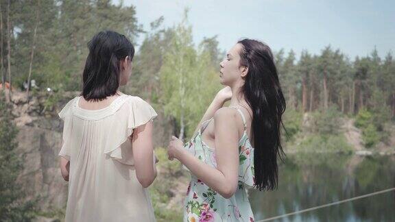 肖像两个可爱迷人的年轻女子穿着夏装看着惊人的自然景色