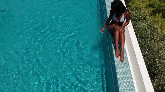 鸟瞰图一个女人日光浴的无边泳池