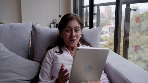 快乐的老女人在家里用平板电脑开视频会议