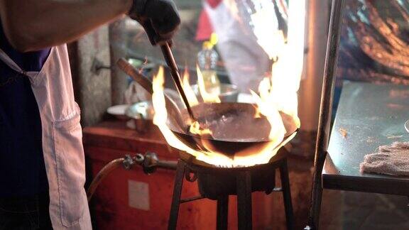 一名亚洲男子在泰国街头用火烹饪泰式炒面